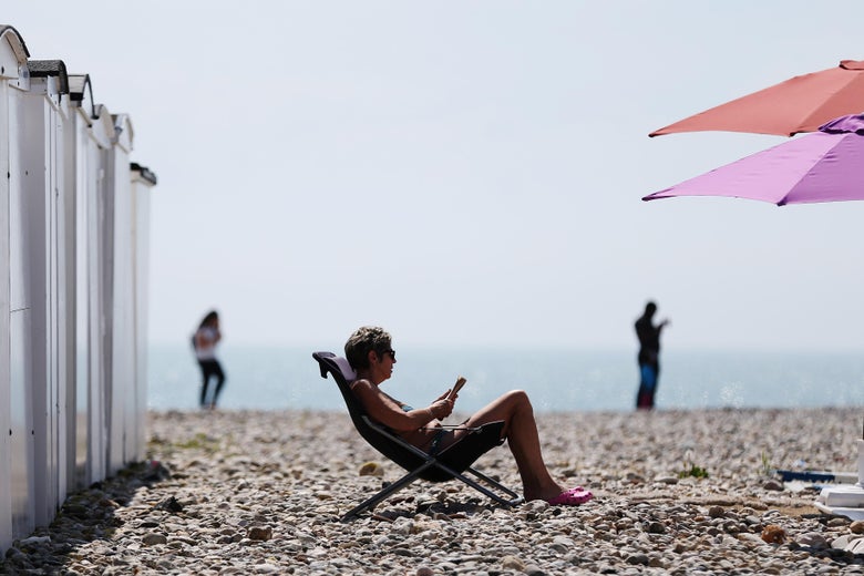 A woman sits on the beach in a deck chair reading on a sunny day in Le Havre, northwestern France, on May 27, 2016.